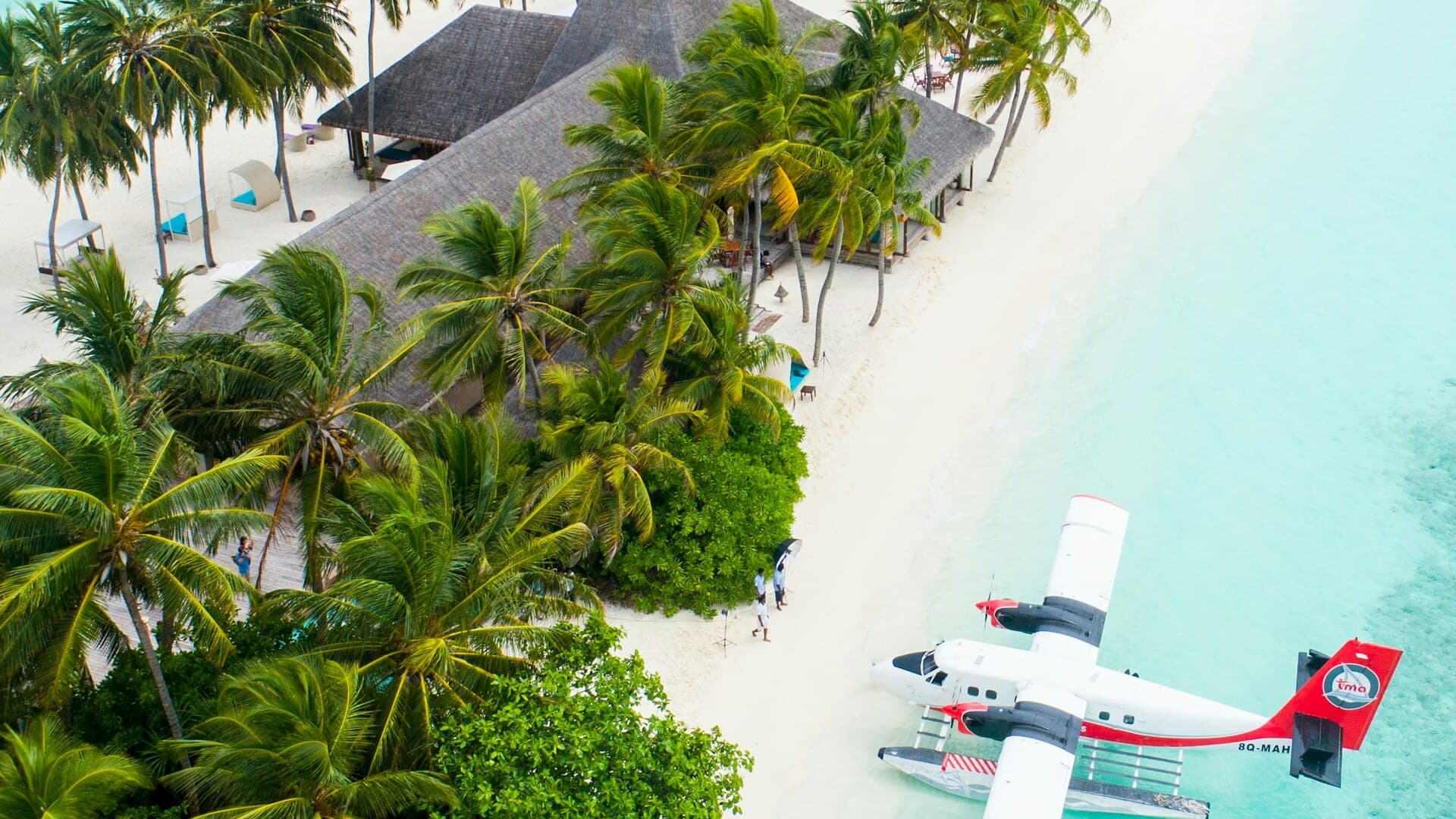 Traveler reviewing plans at a luxury resort table overlooking turquoise water