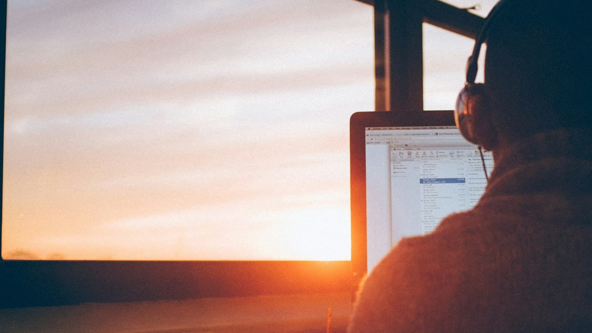 Remote professional working on a laptop as sunrise light floods an open-air balcony