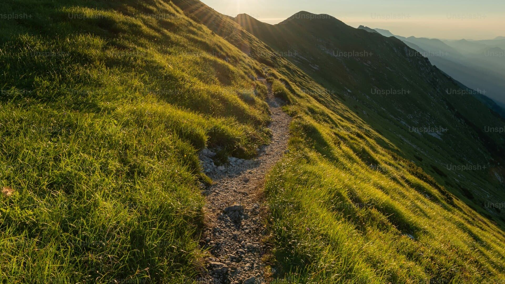 Solo hiker walking toward a sunlit mountain ridge